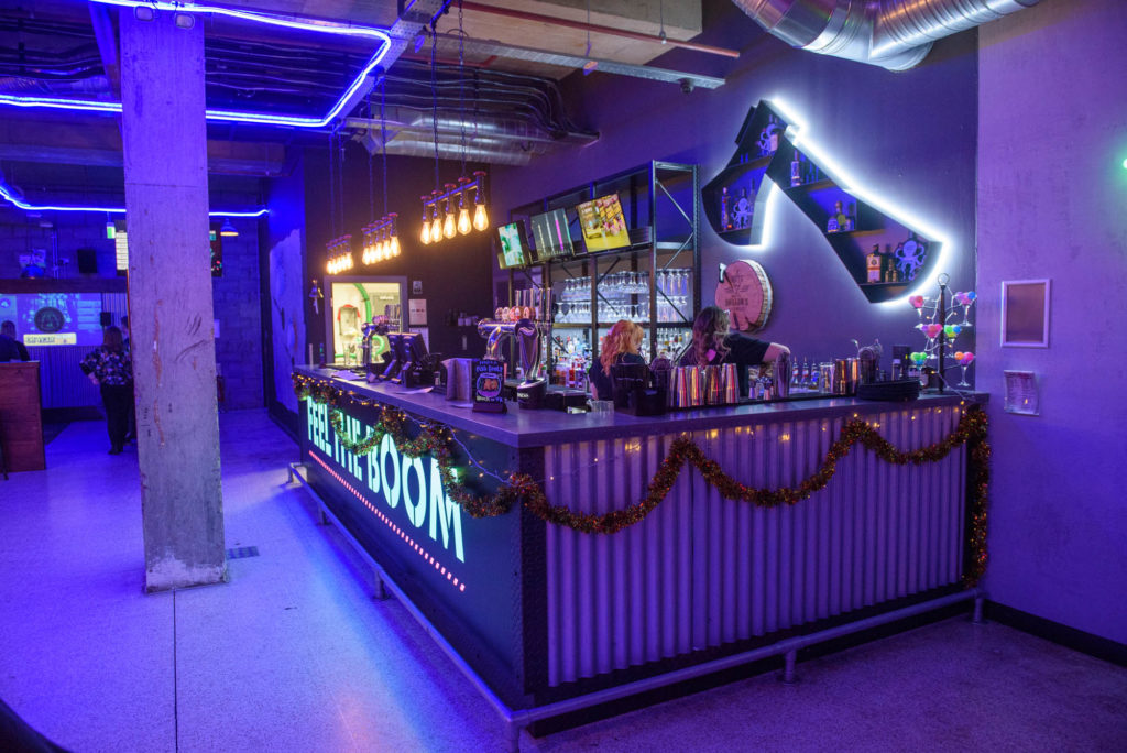 A vibrant bar illuminated by colorful neon lights, featuring a prominent neon sign that adds to the lively atmosphere.