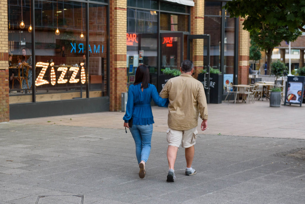 A couple strolling down a sidewalk, enjoying each other's company.